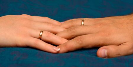 Photo of two hands with beautiful wedding rings on blue background