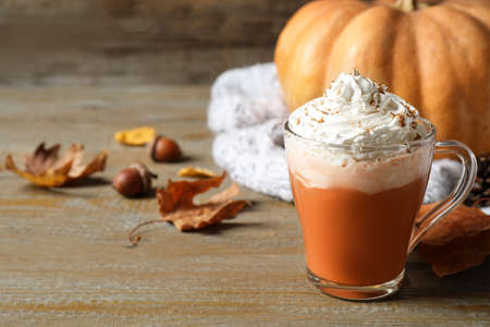 Pumpkin spice latte with whipped cream in glass cup on wooden table ...