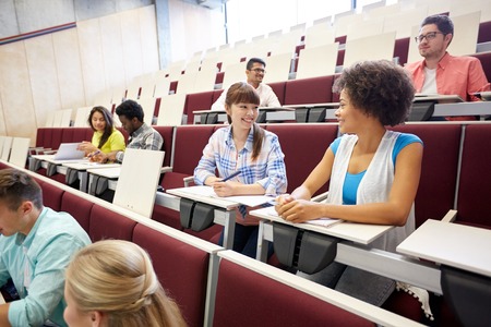 education, high school, university, learning and people concept - group of international students talking on lecture