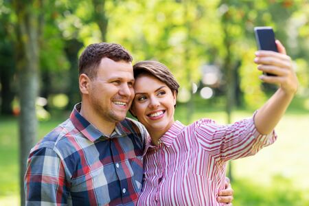 happy couple in park taking selfie by smartphone - Stock Image - Everypixel