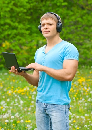 Young man working with a laptop and listening music on headphone ...
