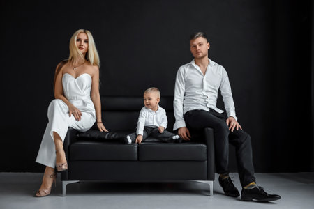 Photo of a beautiful European married couple, a young girl and a guy with a little son, posing together in front of the camera. Black background, concept of modern family, family relationships