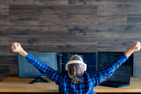 Back view of man freelancer in white headphones is working at home ...
