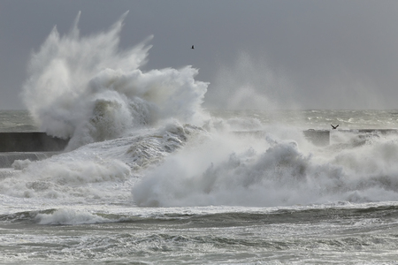 Big splash from storm waves breaking over rocks and pier - Stock Image ...