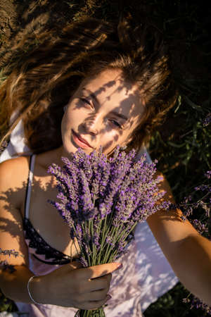 Relaxed pretty woman breathing fresh air sitting in a lavender field a ...
