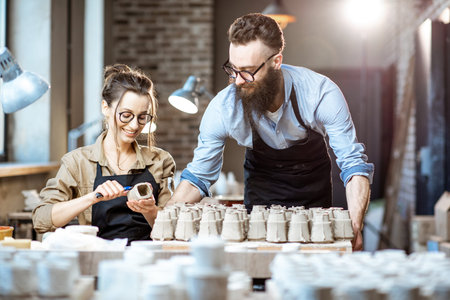 Man and woman working with clay workpieces making ceramic products at ...