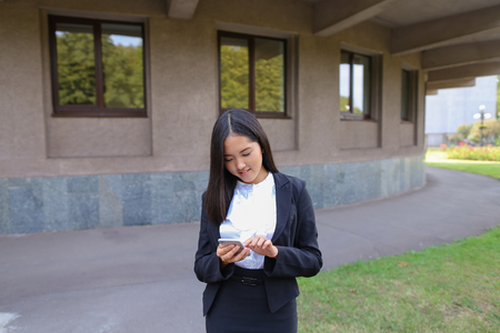 Beautiful cheerful young female international student girl holding phone, smiling, laughs