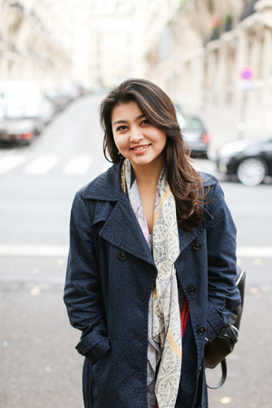 Chinese smiling girl standing in street background, walking after classes. Concept of international students and strolling in city.