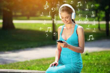 Young woman with headphones on green grass in the park - Stock Image ...
