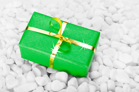 Small green and gold gift box on a background of white stones - Stock ...