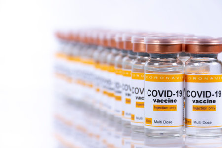 Two rows of vials with coronavirus vaccine on white table with ...