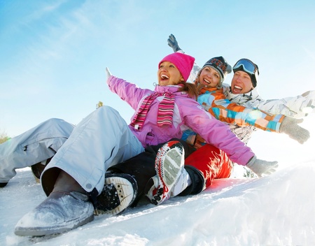 Group of teenagers slide downhill in wintertime