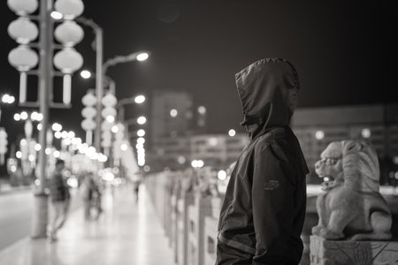 Hooded man in the street at night, black and whiteの写真素材