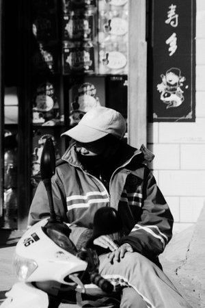 Person in protective mask sitting on the street in Ho Chi Minh cityの写真素材