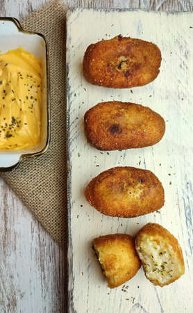 top view of four croquettes on a white board and a cheese sauceの写真素材