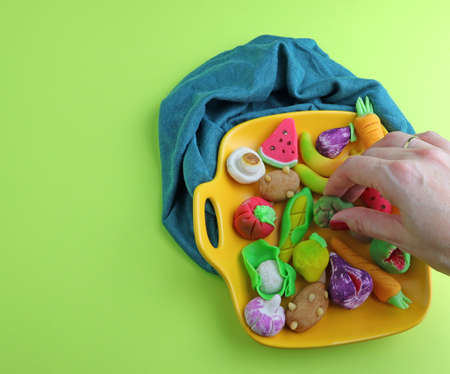 view from above of a yellow plate with typical marzipan from the 9th of October in Valencia, Spain, and a human hand holding one. The green color background and copy spaceの写真素材