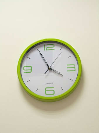 Green clock on white wallの写真素材