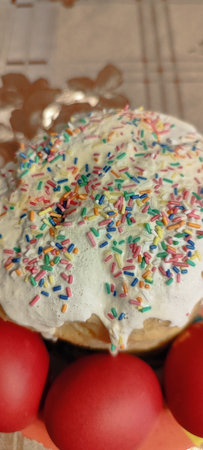 Traditional Easter cake with sprinkles and icing. Red eggs with Easter cake.