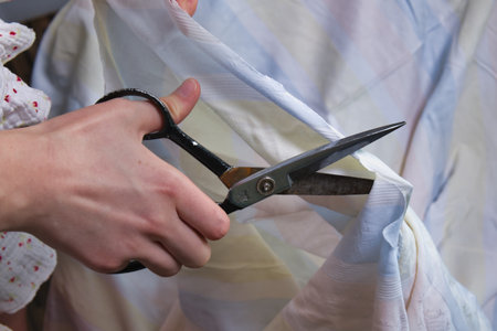 Close-up of the hands of a seamstress cutting fabric with scissors