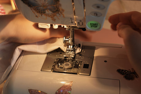 Detailed Shot of Expert Hands Using a Sewing Machine on Soft White Fabric in a Cozy Creative Studio...