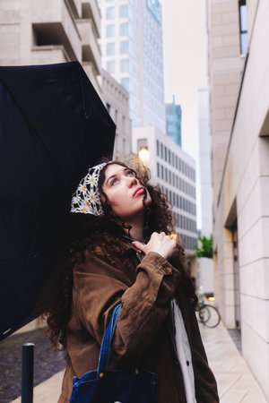 Young Woman with Umbrella Posing Creatively in Modern Urban Cityscape on a Rainy Day