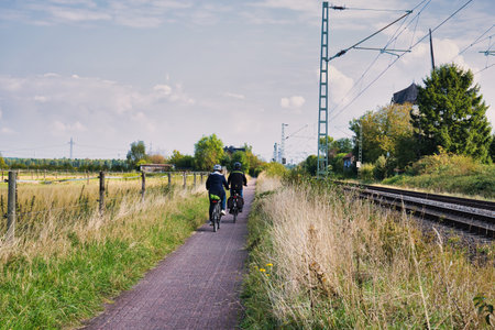 Cyclists cycling along the railway track in the countryside on a sunny day