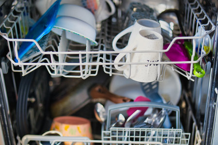 Dishwasher full of dirty dishes in the kitchen. Selective focus