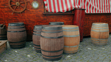Experience the rustic charm of wooden barrels lined up by a vibrant striped boat at a lively market.の写真素材