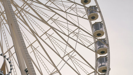 A large Ferris wheel stands tall at an amusement park during a cloudy day, waiting for visitors to ride.の写真素材