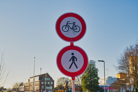 In Neuss, Germany, a bicycle sign and a pedestrian sign are prominently displayed under a bright blue sky. This scene captures city planning and traffic regulations in a bustling urban environment.の写真素材