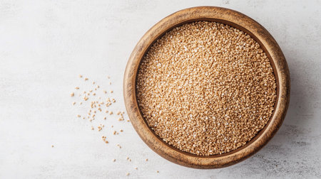 Oatmeal is neatly arranged in a round wooden bowl on a bright surface, highlighting its texture and color.の素材