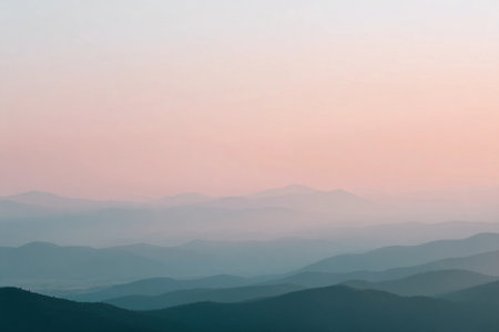 Warm pastel colors fill the sky as sunlight fades behind the mountains at sunset.の素材