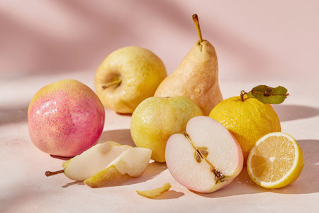 Fresh apples and pears arranged in a still life, highlighting their vibrant colors on a soft pastel surface.の素材