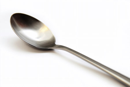 A steel spoon is placed on a plain white background. It is suitable for serving or eating food.の素材