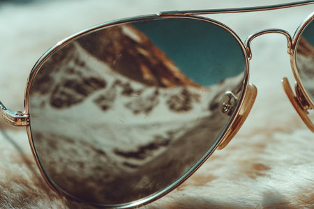 Sunglasses reflect a mountain scene, highlighting outdoor exploration and travel moments in bright weather.の素材