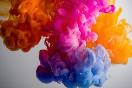 Bright ink clouds mix in clear liquid, creating vivid colors in an artistic display.の素材