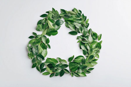 Fresh green leaves form a circle on a simple surface, showing natural shapes and colors of leaves.の素材
