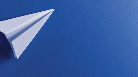 A paper airplane sits in the corner on a blue surface, suggesting a startup launch or creative idea.の素材