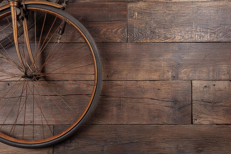 Bicycle wheel is shown on wooden planks, creating space for writing or design. It captures simple beauty and stillness.の素材