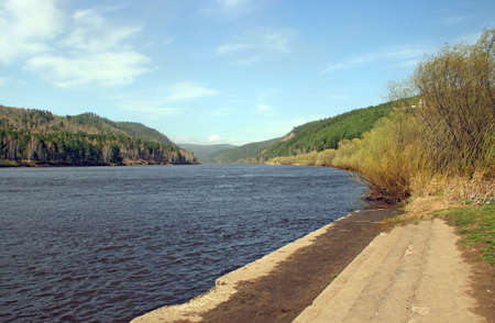 Wide concrete steps lead to the river. There is an amazing view of the water ripples and wooded hills in the distance.の写真素材