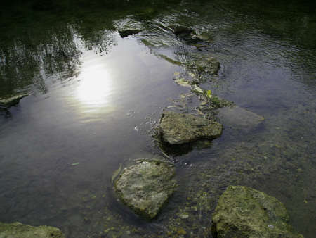 Rocks in the water and the reflection of the sun's disk. View from above.の写真素材