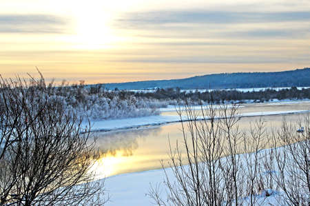 Winter river runs between snowy shores and the color of sky create just fantastic landscape.の写真素材