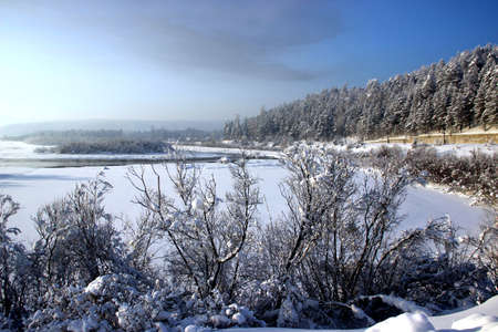 Winter landscape - the river runs between snowy shores and woody hills.の写真素材