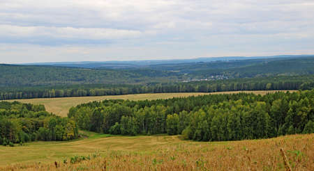 Amazing autumn landscape - view from a hill on a hilly area under a gloomy autumn sky.の写真素材