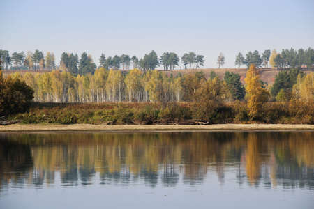 Calm and relaxation emanate from the amazing autumn landscape of the water surface, where colorful trees and sky are reflected.の写真素材