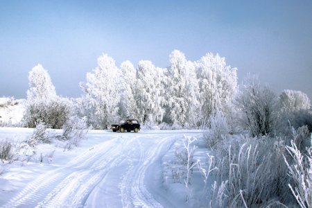 A clear winter day. Clear frosty blue sky. A lone car at a fork in the road.の写真素材