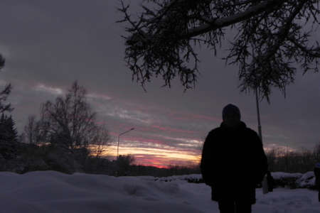 A silhouette of a person against the background of the sunset sky in the dark time of the day in winter.の写真素材