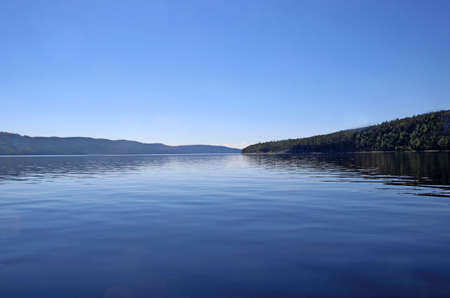 Amazing blue river water and endless blue sky, and only a thin strip of shore separating themの写真素材