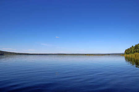 Amazing blue river water and endless blue sky, and only a thin strip of shore separating themの写真素材