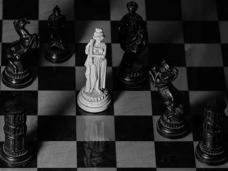 White queen and black figures on chessboard in black and whiteの写真素材